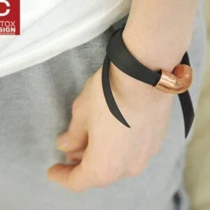 Zdjęcie kobiecego nadgarstka z przestrzenną bransoletką z płaskiego kauczuku i przestrzennej rury z miedzi. Czarna bransoletka FUKUI09 unisex zachwyca również na męskim nadgarstku jaka biżuteria na wiosnę modna na prezent
