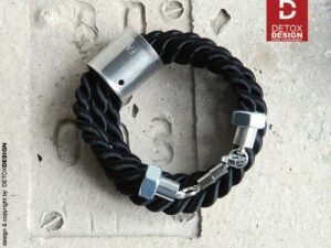 Detoxdesign Współczesna czarna bransoletka OGA06 to unisex w kolorze czarnym wykonana ze sznurów satynowych w tulei ze stali i z zakończeniami ze stali oraz wygodnym zapięciem magnetycznym wykonanym ze stali chirurgicznej
