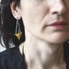 Współczesne długie kolczyki NAGANO47 noszone przez kobietę na zdjęciu zachwycają swoją szlachetną geometrią