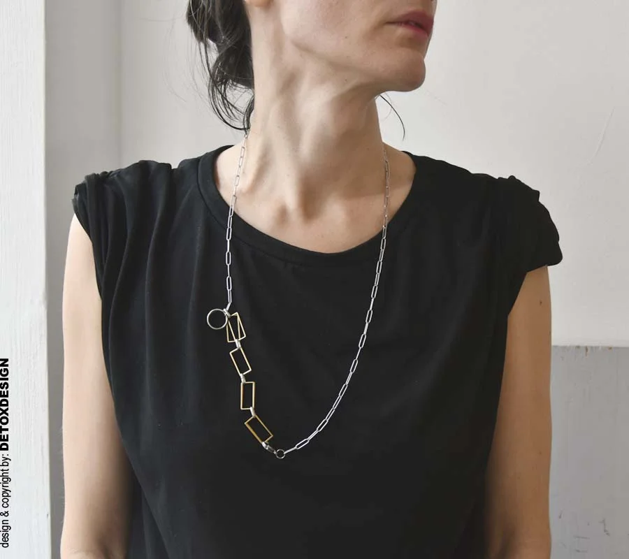 Projektowana przez nas autorska, oryginalna i modna biżuteria zachwyca i zaskakuje czego przykładem jest widoczny na zdjęciu długi naszyjnik AOMORI05 bo ma dowolną długość, możliwość noszenia w różny sposoób a w dodatku to współczesna bransoletka geometryczna.