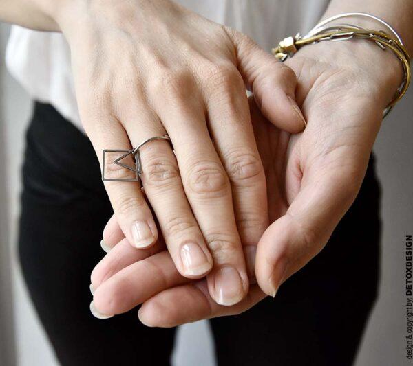 Geometryczny pierścionek na kobiecej dłoni widocznej na zdjęciu wygląda obłędnie.