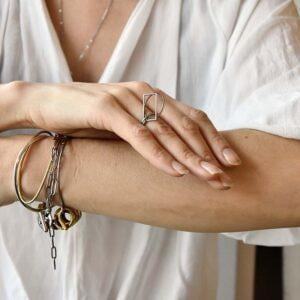 Prosty srebrny pierścionek na zdjęciu zachwyca swoim minimalistycznym i mobilnym oraz geometrycznym charakterem.