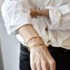 Minimalistyczna bransoletka na zdjęciu pokazana na kobiecym nadgarstku to zachwycająca przestrzenna złota bransoletka NAGANO40 wykonana z mosiądzu i stali chirurgicznej