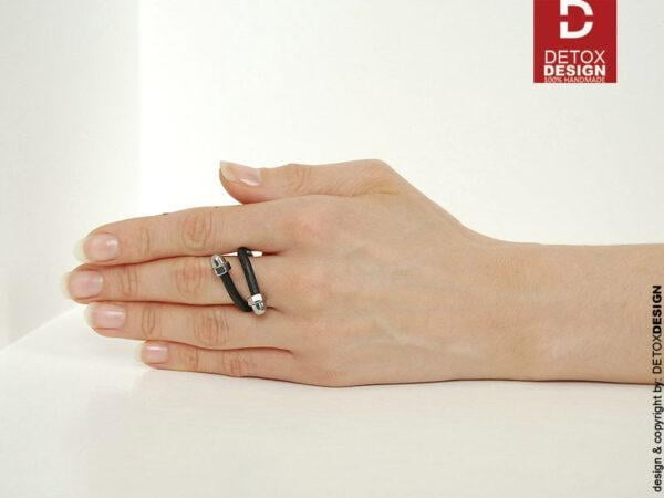 Czarny pierścionek KOBRO01, którego rozmiar i kształt można dowolnie regulować widoczny na kobiecej dłoni.