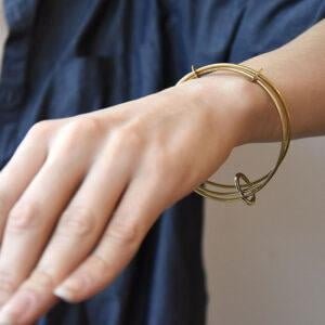 Zdjęcie przedstawia dłoń kobiecą a na niej zachwycająca współcześnie elegancka złota bransoletka NAGANO03 z mosiądzu jaka biżuteria na wiosnę modna modne bransoletki prezent