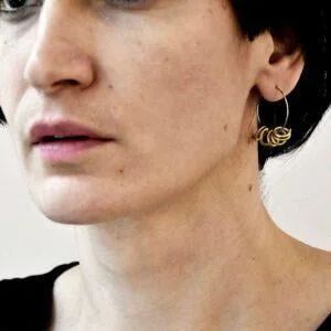 Kobieta na zdjęciu nosi nasze autorskie kolczyki koła NAGANO 14 i wygląda zachwycająco