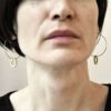 Zdjęcie przedstawia widok z przodu na subtelnie techniczne i zachwycające współczesną elegancją kolczyki z mosiądzu i stali chirurgicznej