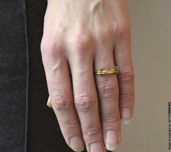 Współcześnie lekki i elegancki złoty pierścionek 'NAGANO'03 z mosiądzu widać na zdjęciu na palcu kobiecym a pierścionek zachwyca lekkością i subtelnie technicznym charakterem.