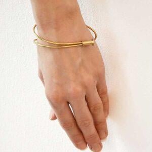 Zdjęcie przedstawia dłoń kobiety widoczną z przodu z unikalną bransoletką na nadgarstku to złota bransoletka NAGANO04