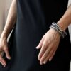 Zdjęcie kobiety w czarnej sukience a na nadgarstku wyrazista w formie bransoletka damska IKI01 jaka biżuteria na wiosnę modna na prezent