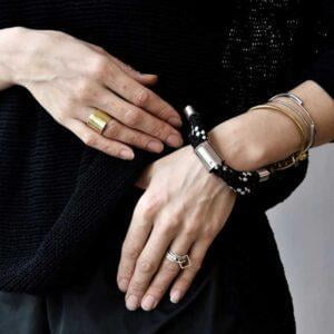 Nasza autorska bransoletka IKI29 z czarnej liny na kobiecym nadgarstku widziana na zdjęciu z przodu i to jest wzór biżuterii unisex i te bransoletki kochają również mężczyźni jaka biżuteria na wiosnę modna na prezent