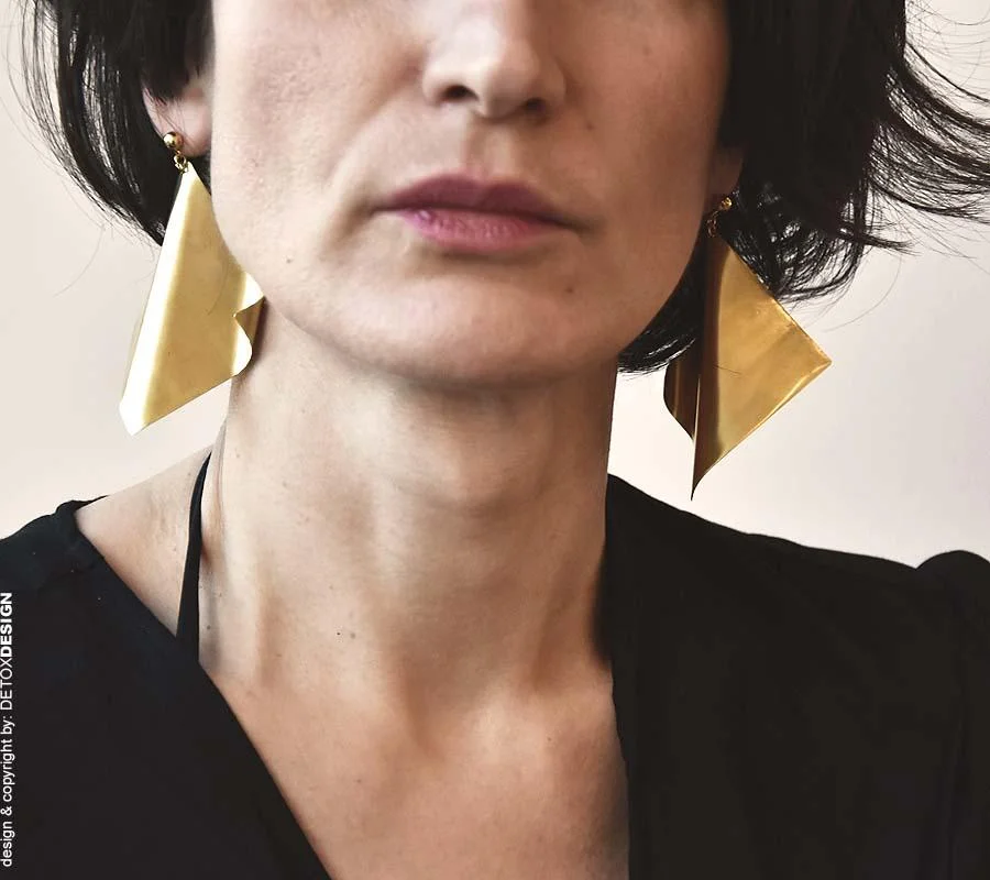 Na zdjęciu kobieca twarz widoczna z przodu a na uszach przepiękne poetyckie kolczyki z mosiądzu.