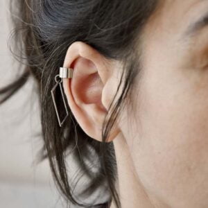 Widoczna na zdjęciu na kobiecym uchu geometryczna nausznica z prostokątem KOBE03 to modna i oryginalna biżuteria.