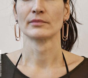 Wyrazista biżuteria DETOXDESIGN – duże kolczyki industrialne Oryginalne kolczyki Nagano80 z miedzi w kształcie dużych spinaczy wiszące przy twarzy projektantki DETOXDESIGN.