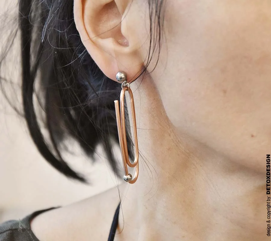 Oryginalne kolczyki NAGANO80 widoczne na kobiecym uchu w zbliżeniu intrygują i zachwycają bo to oryginalna i modna, industrialna biżuteria autorska