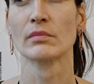 Oryginalne kolczyki Nagano81 z miedzi w kształcie spinaczy subtelnie wiszące przy twarzy projektantki DETOXDESIGN.