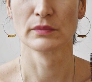Minimalistyczne duże kolczyki koła Nagano83 z mosiężną spiralą zdobiące uszy projektantki DETOXDESIGN.