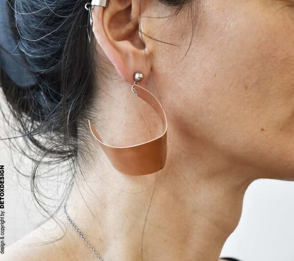 Miedziane kolczyki NAGANO84 na zdjęciu widok z boku na kobiecym uchu pokazuje, że to oryginalne i modne kolczyki