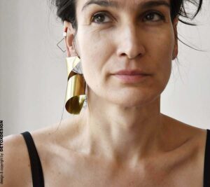 Duże kolczyki mosiężne Nagano87 o szerokiej, trójwymiarowej strukturze widoczne od przodu na uszach projektantki DETOXDESIGN.